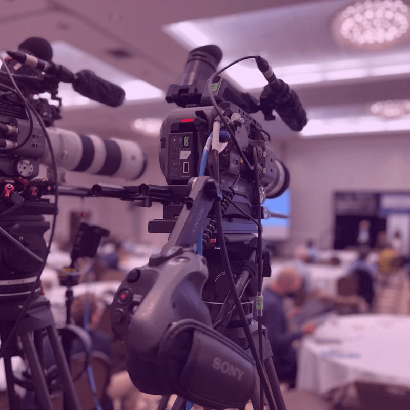 camera equipment behind the crowd of an ongoing corporate event production