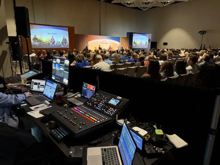 View from the show desk at a corporate general session, with monitors up front and a full ballroom.