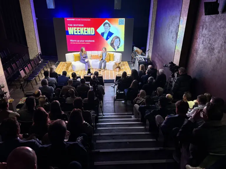 A live video podcast set with a couch, an LED wall, cameras and a seated audience.