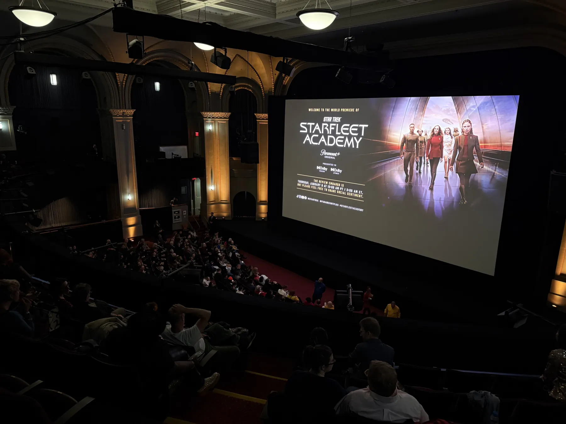 A wide view of a darkened historic theater during a premiere screening on the big screen.