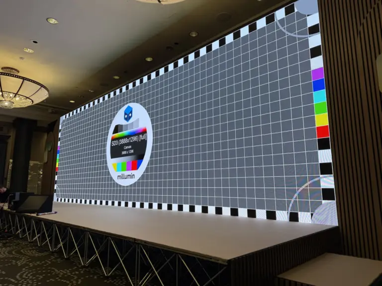 An LED wall mid-build in a hotel ballroom, showing a grid test pattern above an empty stage.