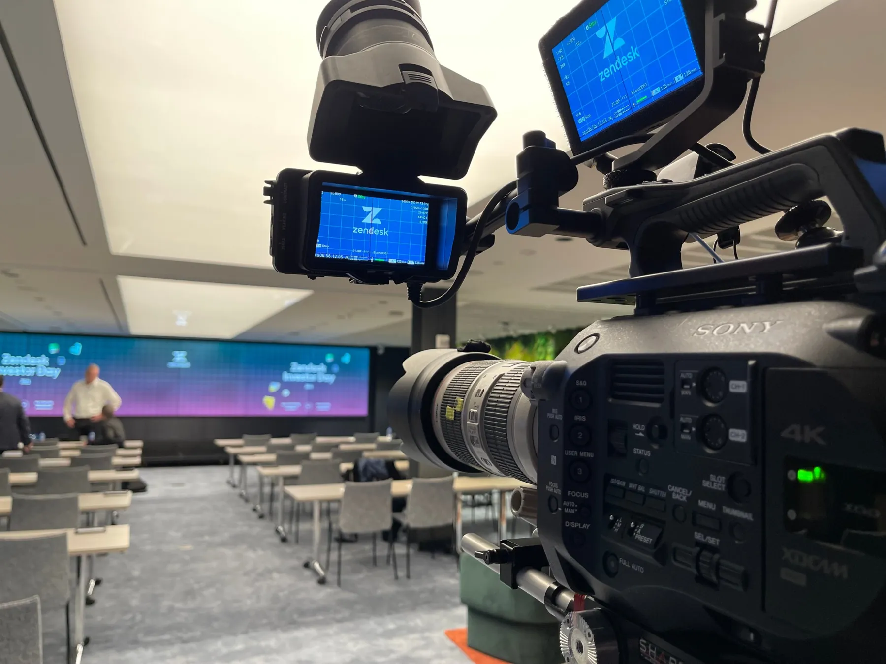 A broadcast camera trained on the Zendesk Investor Day stage, its monitor showing the Zendesk logo, before doors.