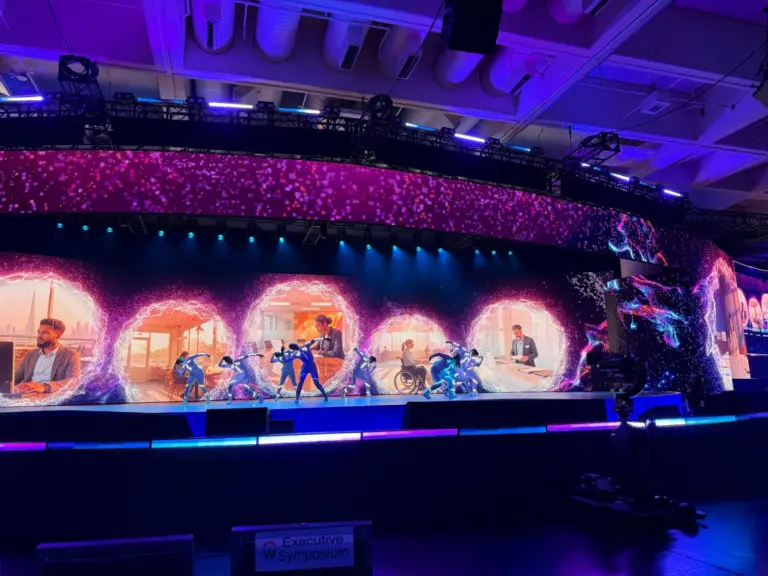 Dancers in light-up costumes perform the opening act of the Workday Rising 2025 keynote in front of a wraparound LED wall.
